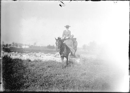 Horse sports, Mrs. Arthur Aldis, riding sidesaddle on a horse as it jumps a stone wall - Chicago Daily News, Inc.