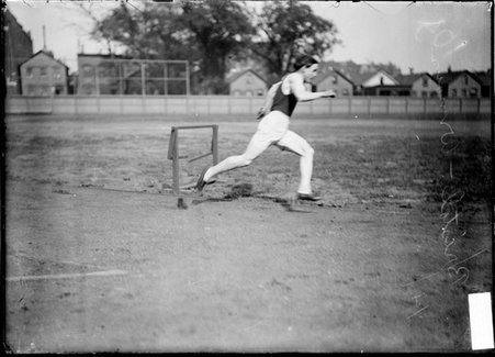 Athlete, G. Bristol, running on the inside lane of a track at an athletic field - Chicago Daily News, Inc.