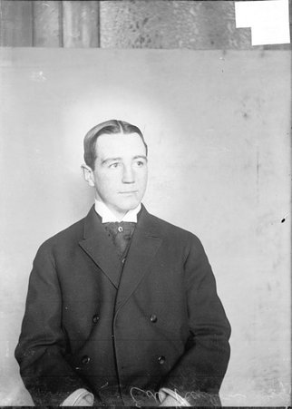 Pugilist, Eddie Hanlon, sitting in front of a light colored backdrop in a room - Chicago Daily News, Inc.