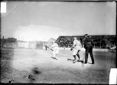 Chicago Cubs baseball player Chance, running toward first base and a catcher and umpire looking toward left field at West Side Grounds - Chicago Daily News, Inc.