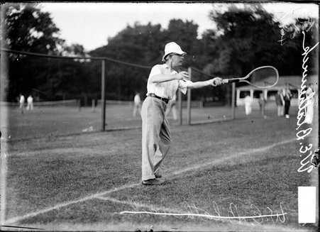 Tennis player W. E. Blatkerwick, standing at the baseline swinging a racquet with his left hand on a court at a tennis club - Chicago Daily News, Inc.