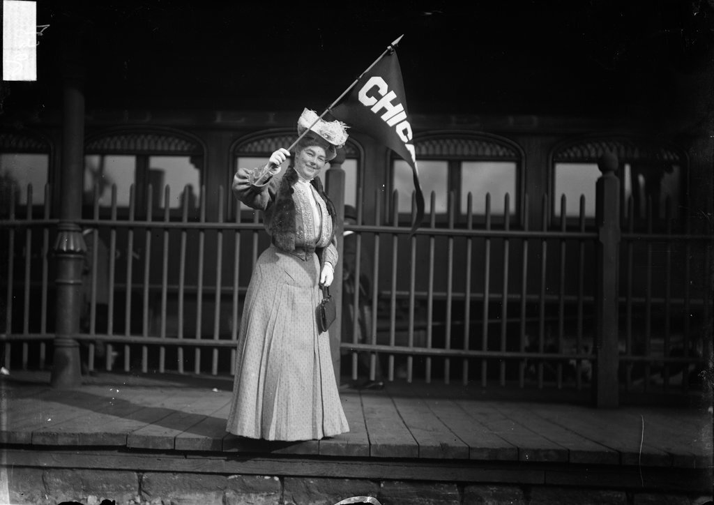 Woman waving a Chicago pennant standing on a train station platform - Chicago Daily News, Inc.