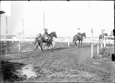 Horse racing, men riding horses through a gate at Harlem Race Track - Chicago Daily News, Inc.