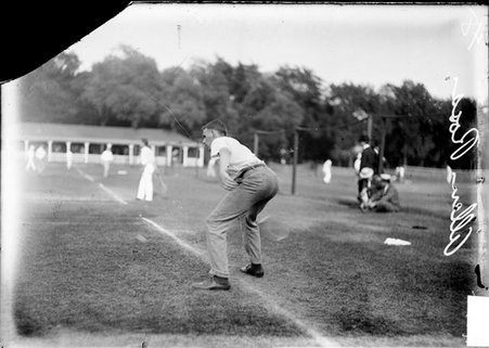 Tennis player Allen Ross, bending forward and swinging his racquet near the ground on a court at a tennis club - Chicago Daily News, Inc.
