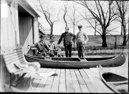 Rowers, Lincoln Park Rowing Club, posing on the dock at the boat house, a canoe is sitting on the dock in front of them - Chicago Daily News, Inc.