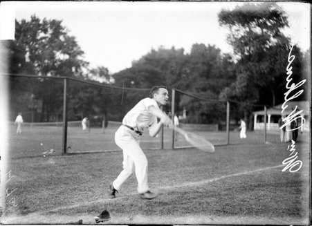 Tennis player William Wilkins, running forward from the baseline swinging his racquet on a grass tennis court at a club - Chicago Daily News, Inc.