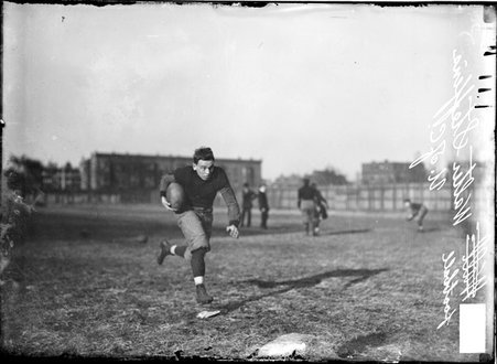 University of Chicago football player Walter Steffen, holding the ball in his right arm, running with his head down, toward camera - Chicago Daily News, Inc.