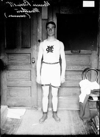 Marathon runner Dennis Bennett, standing in front of wooden doors in an office, facing the camera - Chicago Daily News, Inc.