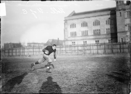 University of Chicago football player Noll, holding a football in his right arm and running at Marshall Field - Chicago Daily News, Inc.
