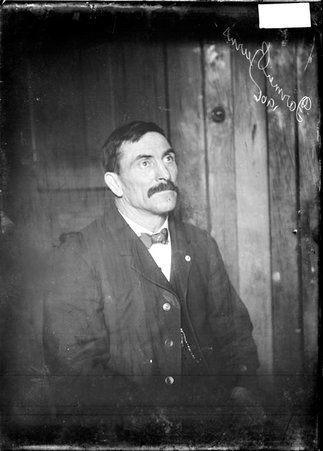 Wrestler Farmer Burns, turned to the right of the image, sitting in a chair in a room - Chicago Daily News, Inc.