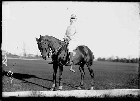 Polo player W. Vernon Booth, holding a mallet sitting on top of a polo pony on a polo field - Chicago Daily News, Inc.