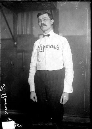 Bowler, Louis Simons, wearing a long sleeved shirt emblazoned with the word Lipman's, standing in a room - Chicago Daily News, Inc.