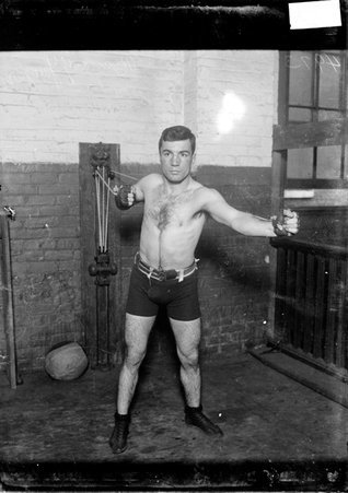 Boxer Benny Yanger, exercising on a resistance machine in a gymnasium - Chicago Daily News, Inc.