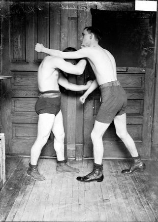 Boxer, Kid Herman, giving a right upper cut to his unidentified opponent's jaw, in a room in the Chicago Daily News building - Chicago Daily News, Inc.