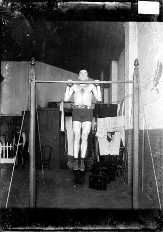 Boxer Benny Yanger, performing pull-ups on a bar in a gymnasium - Chicago Daily News, Inc.