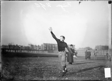 University of Chicago football player Finger, standing with one arm raised in the air and the other out to his side at Marshall Field - Chicago Daily News, Inc.