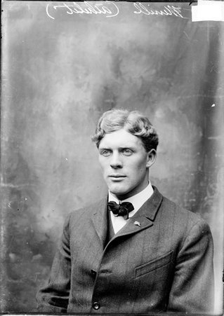 Athlete N. Merrill, sitting in a chair in front of a backdrop in a stairwell hallway at the Chicago Daily News building - Chicago Daily News, Inc.