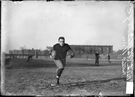 University of Chicago football player Walter Steffen, holding the ball in his right arm, running with his head up, toward camera - Chicago Daily News, Inc.