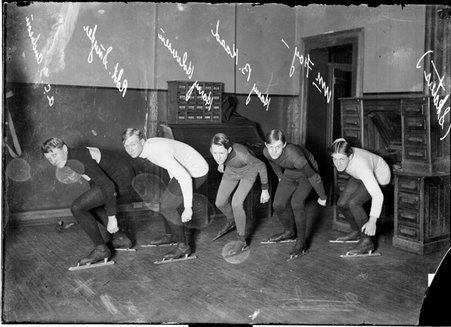 Skaters, Wm. Foy, Harry B. Kaad, Halverson, Robt. Snyder, and A. C. G. Anderson, wearing ice skates, leaning over in a gymnasium - Chicago Daily News, Inc.