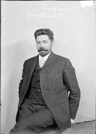 Chess player, C. Madsen, sitting on chair in front of a light colored backdrop in a room - Chicago Daily News, Inc.