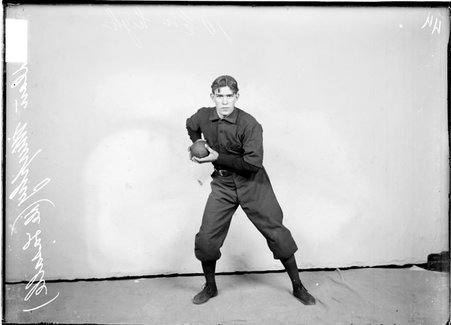Baseball player, De LaSalle, Dan Murphy, holding ball in both hands at chest level in front of a light colored backdrop in a room - Chicago Daily News, Inc.