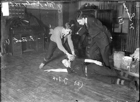 Indoor baseball players, McKinley High School, posing in an office, Bate tagging Fox out while Simons calls the play - Chicago Daily News, Inc.