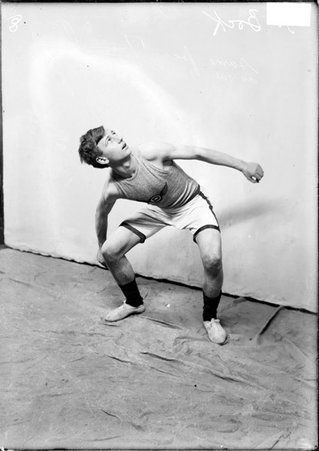 Basketball player H. Bock, Dorian, looking up and crouching in front of a light-colored backdrop - Chicago Daily News, Inc.