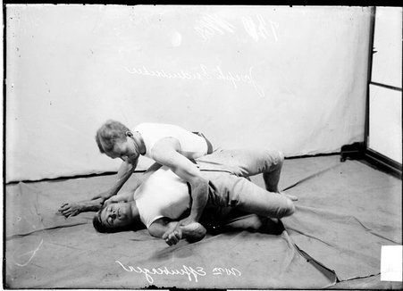Wrestlers, Joseph Seidenbecker and William Effenberger, Seidenbecker holding Effenberger by the forearms, kneeling in front of backdrop - Chicago Daily News, Inc.
