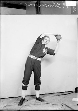 Indoor baseball player Thronson, holding an indoor baseball above his head and leaning to his left, standing in front of a backdrop - Chicago Daily News, Inc.