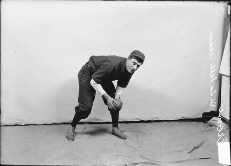 Indoor baseball player, De LaSalle, Crowe, leaning forward and holding an indoor baseball, standing in front of a light-colored backdrop - Chicago Daily News, Inc.