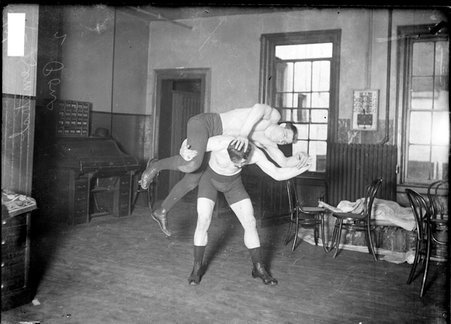 Wrestler, Demetral and Pons, one wrestler holding the other across his shoulders in an office - Chicago Daily News, Inc.