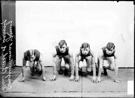 Runners E. W. Clement, W. R. Franklin, H. H. Park, and B. W. Hughes, crouching in ready positions in front of a backdrop in a room - Chicago Daily News, Inc.