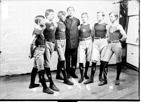 Wrestlers, Social Turners, H. Fott, Rassenheim, Helfrick, Barre, Armbruster, Hawke, and J. Fott, standing in front of a backdrop - Chicago Daily News, Inc.
