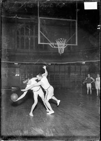 Basketball players, John Schommer and Houghton, Schommer attempting a shot, Houghton blocking, in a gymnasium - Chicago Daily News, Inc.