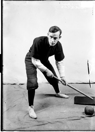 Indoor baseball player, Jimmy Baxter, holding a baseball bat, standing in a bunting stance in front of a backdrop in a room - Chicago Daily News, Inc.