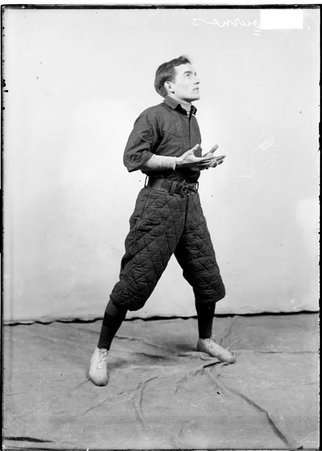 Indoor baseball player William Bourne, looking up and holding his hands close to his body, standing in front of a backdrop - Chicago Daily News, Inc.