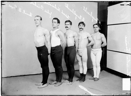 Wrestlers, Lincoln Turners, E. Englebrecht, H. Englebrecht, Hohnstock, Pause, and Bichele, gathered in front of a backdrop in a room - Chicago Daily News, Inc.
