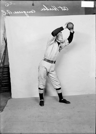 Indoor baseball player, Congress Athletic Club, Art Hieber, holding a ball in both hands over his head in front of backdrop - Chicago Daily News, Inc.
