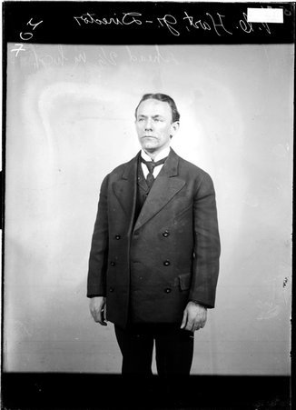 Director V. C. Hart, Jr., standing in front of a light-colored backdrop in a room - Chicago Daily News, Inc.