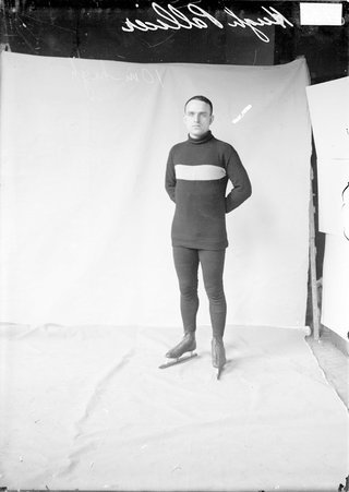 Skater, Hugh Pallicer, standing, wearing ice skates in front of a backdrop - Chicago Daily News, Inc.