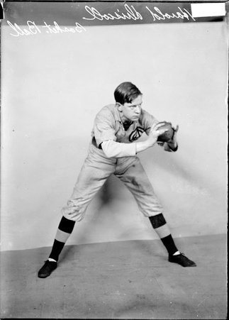 Indoor baseball player, Harold Driscoll, holding ball at chest level in both hands, standing with legs spread in front of a backdrop - Chicago Daily News, Inc.