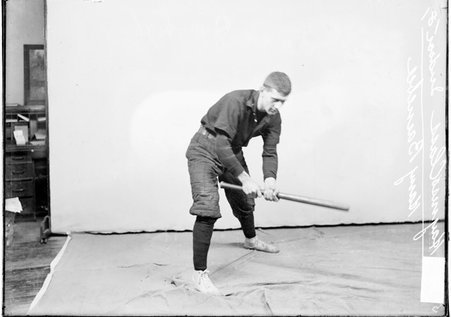 West End indoor baseball player Harry Barnebee, of the Haynes class, holding a bat, standing in a batting stance in front of a backdrop - Chicago Daily News, Inc.
