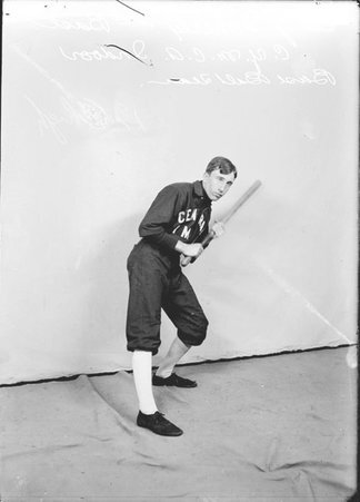 Indoor baseball player, Central YMCA, Ed J. Doherty, leaning back on left leg, holding bat in front of a backdrop in a room - Chicago Daily News, Inc.