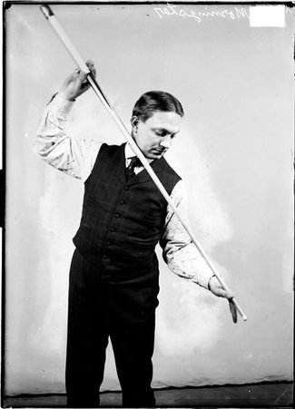 Billiards player, Ora Morningstar, overhand shot position, pool cue grazing chin in front of a light colored backdrop in a room - Chicago Daily News, Inc.