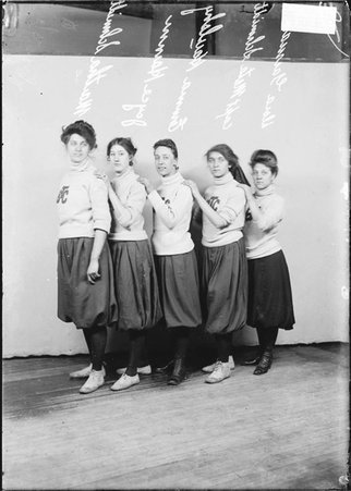 Spalding girls' basketball players Schmidt, Harum, Haulsky, captain Schmidt, and Garman, standing in front of a backdrop - Chicago Daily News, Inc.