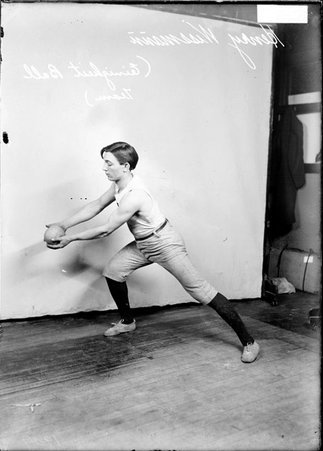 Einigkeit indoor baseball player Wissman, holding a baseball with both arms extended in front of him, lunging in front of a backdrop - Chicago Daily News, Inc.
