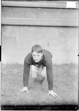 University of Chicago athlete G. H. Young crouching in a ready position in front of a building on the University of Chicago campus - Chicago Daily News, Inc.