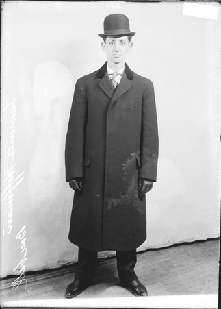 Baseball player Lawrence Hoffman, wearing a suit and hat, standing in front of a light-colored backdrop in a room - Chicago Daily News, Inc.