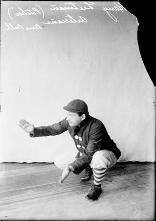 Artesians baseball player Harry Lietman, holding his hands out in front of him, crouching in front of a backdrop in a room - Chicago Daily News, Inc.