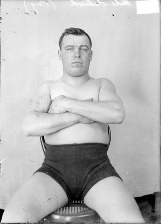 Pugilist Mike Schieck, sitting in front of a light-colored backdrop in a room - Chicago Daily News, Inc.